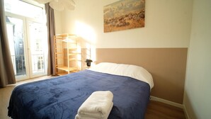 A bedroom with a bed, a window, a painting, and a nightstand. - Smart appart - downtown (Brussels)