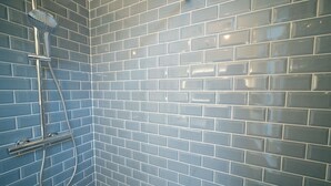 A bathroom with blue-tiled walls and a shower area. - Smart appart - downtown (Brussels)