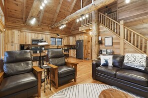 Ein Blockhaus-Innenraum mit Küche, Essbereich und Wohnzimmer.