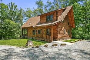 Une cabane en rondins avec un porche, une terrasse et des fondations en pierre.