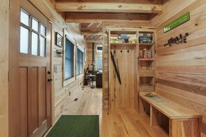 A wooden interior with a bench, shelves with boxes, and a door with a window.