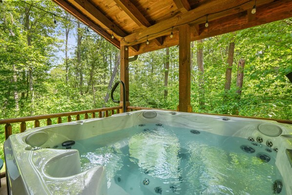 Ein Whirlpool inmitten von Bäumen mit einer Holzterrasse und Geländern.