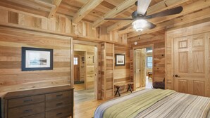 A wooden cabin interior with a bed, dresser, and ceiling fan. - Falling Leaves | Hocking Hills, Accessible, Pets (South Bloomingville)