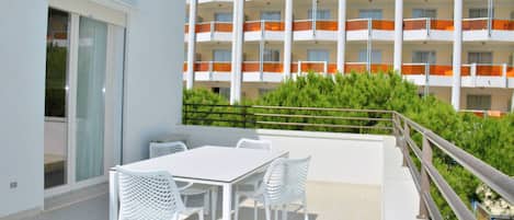 A balcony with a table and chairs, overlooking a building with orange balconies.
