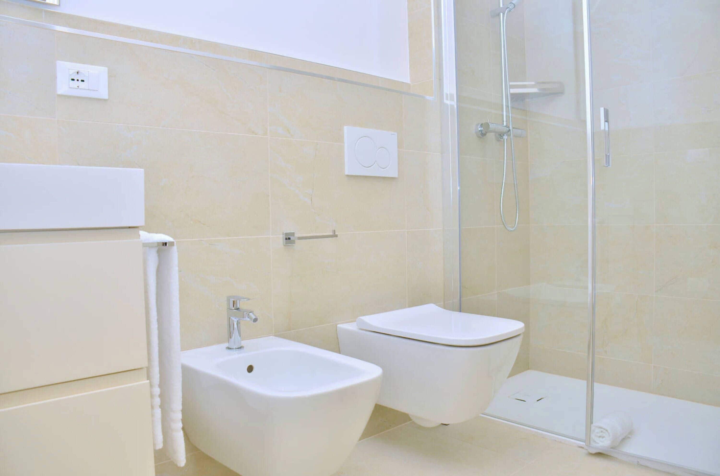 A bathroom with a shower, bidet, and toilet.