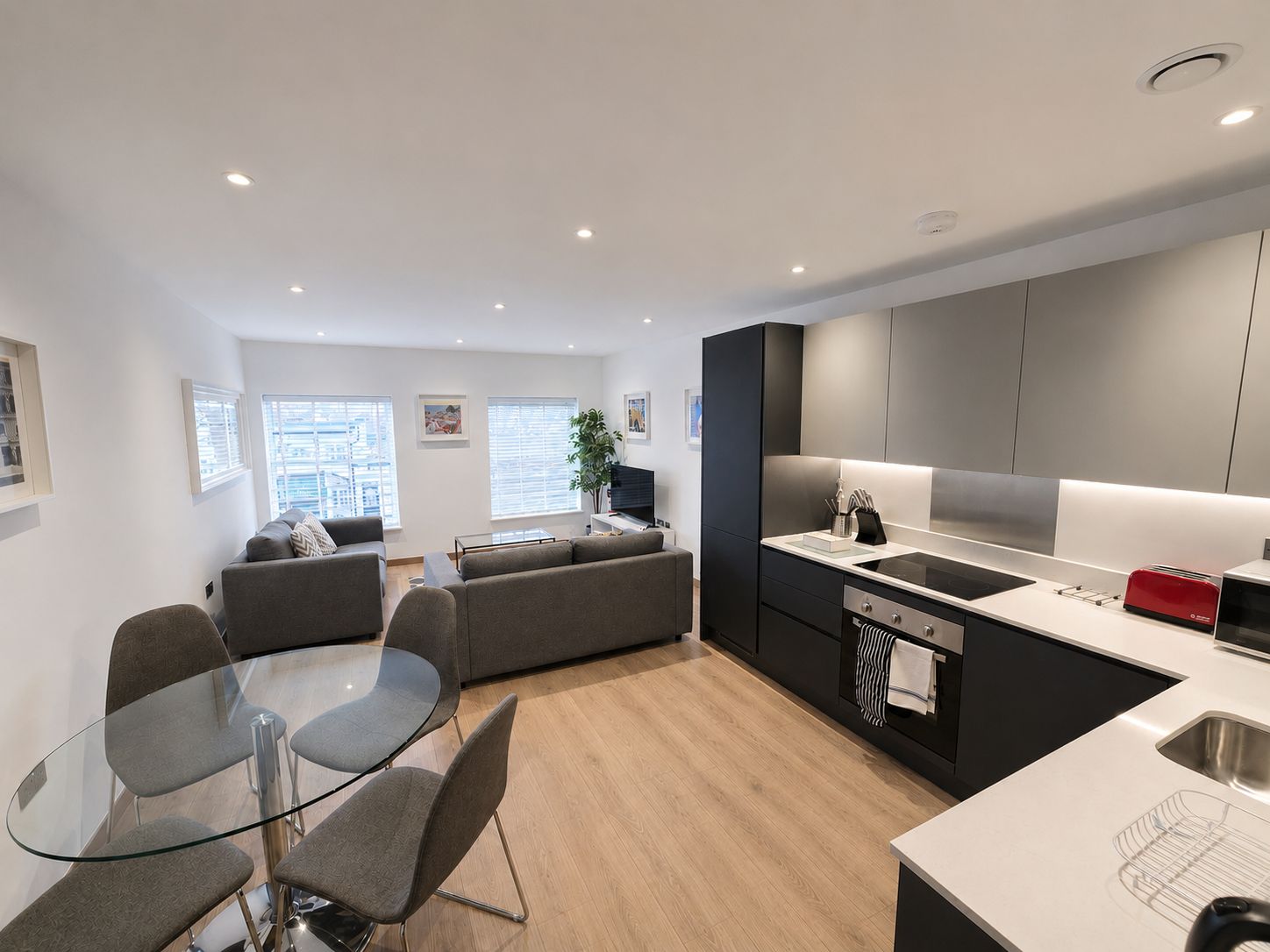A modern apartment with a dining area, kitchen, and living space.