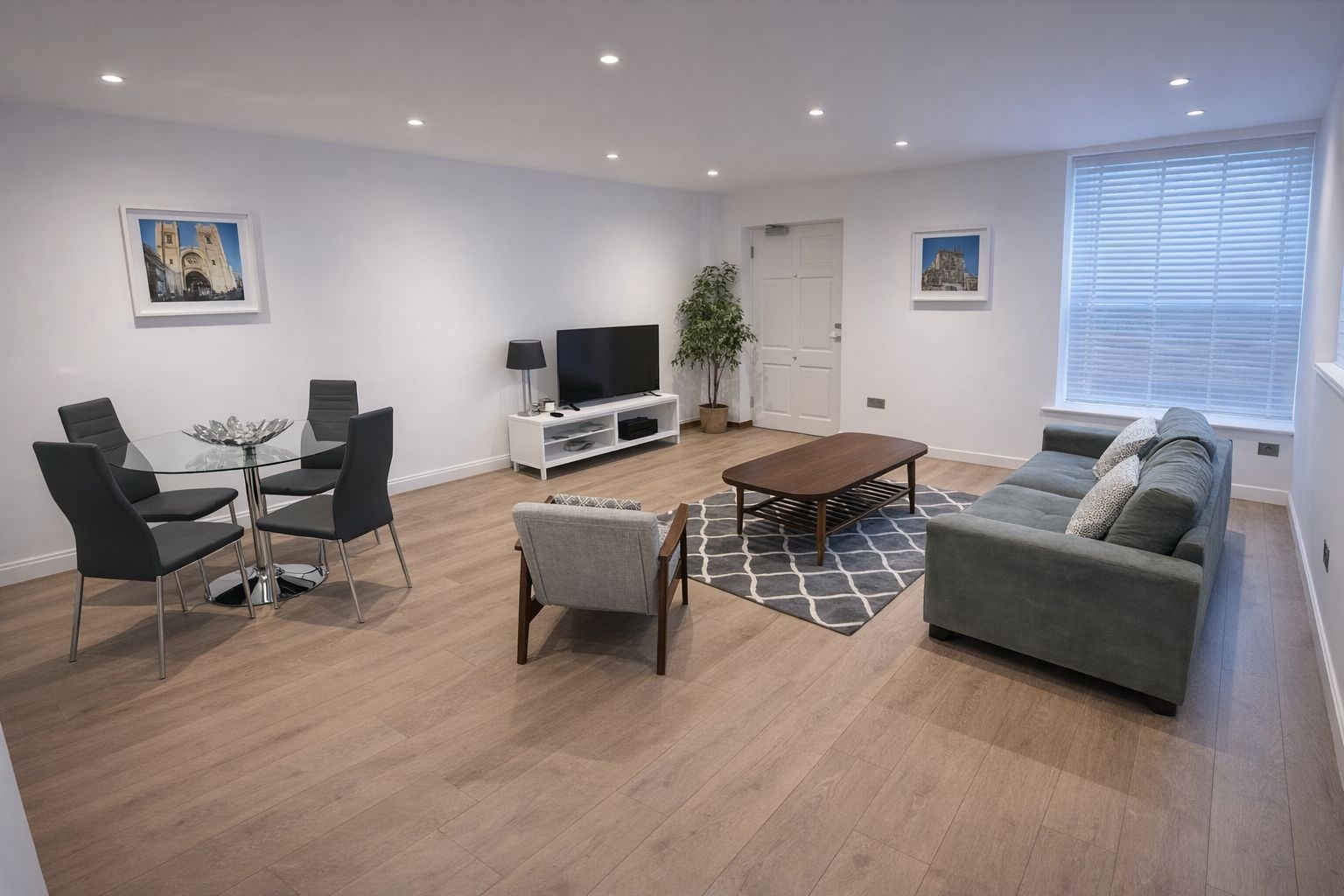Una sala de estar moderna con una mesa de centro de vidrio, un sofá gris y sillas negras.
