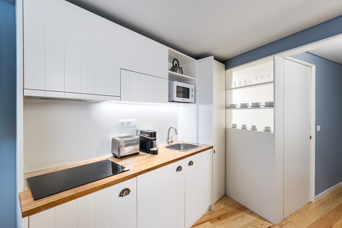 A compact kitchen with white cabinets, a microwave, a toaster, and a coffee maker.