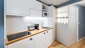 A compact kitchen with white cabinets, a microwave, a toaster, and a coffee maker. - GuestReady - Souto Downtown Studio 1 (Porto)