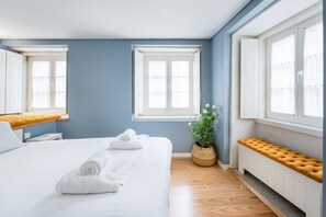 A modern hotel room with a large bed, two windows, a potted plant, and a bench by the window. - GuestReady - Souto Downtown Studio 1 (Porto)