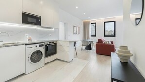 Eine moderne Küche mit einer Bosch-Mikrowelle, Backofen und Waschmaschine, ein Essbereich mit Tisch und Stühlen sowie ein rotes Sofa.