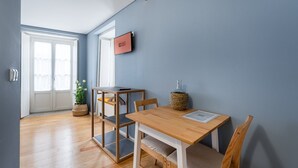 Una habitación moderna con una mesa de comedor de madera, sillas, una mesita auxiliar y una planta en maceta.