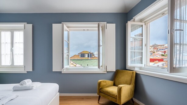 A bedroom with a bed, a yellow armchair, and a window with an open shutter. - GuestReady - Souto Studio 4|4th floor|No elevator (Porto)