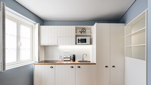 A compact kitchen with white cabinetry, a microwave, a kettle, and a coffee maker on the countertop. - GuestReady - Souto Studio 4|4th floor|No elevator (Porto)