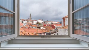 A view through a window of a cityscape with red-roofed buildings and a prominent tower. - GuestReady - Souto Studio 4|4th floor|No elevator (Porto)