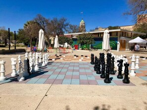 A chessboard set up outdoors with a building and trees in the background. - Create Memories 4BR 3BA Near Riverwalk Downtown (San Antonio)