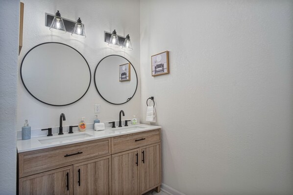 Un baño con dos lavamanos, armarios de madera e iluminación empotrada.