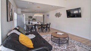 A modern living room with a black sofa, yellow pillow, and a round wooden coffee table. A dining area with a black table and chairs is visible in the background. - Create Memories 4BR 3BA Near Riverwalk Downtown (San Antonio)