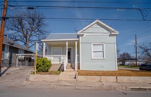 A light blue single-story house with a front porch, a covered entryway, and a small front yard. - Create Memories 4BR 3BA Near Riverwalk Downtown (San Antonio)