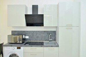 Cocina compacta con lavadora, microondas y lavamanos.