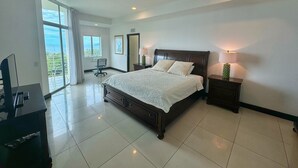 A modern bedroom with a large bed, a desk, and a chair. There is a window with a view of the outdoors. - Duplex Penthouse with Ocean View in Tamarindo, 5 min walk to the beach (Tamarindo)