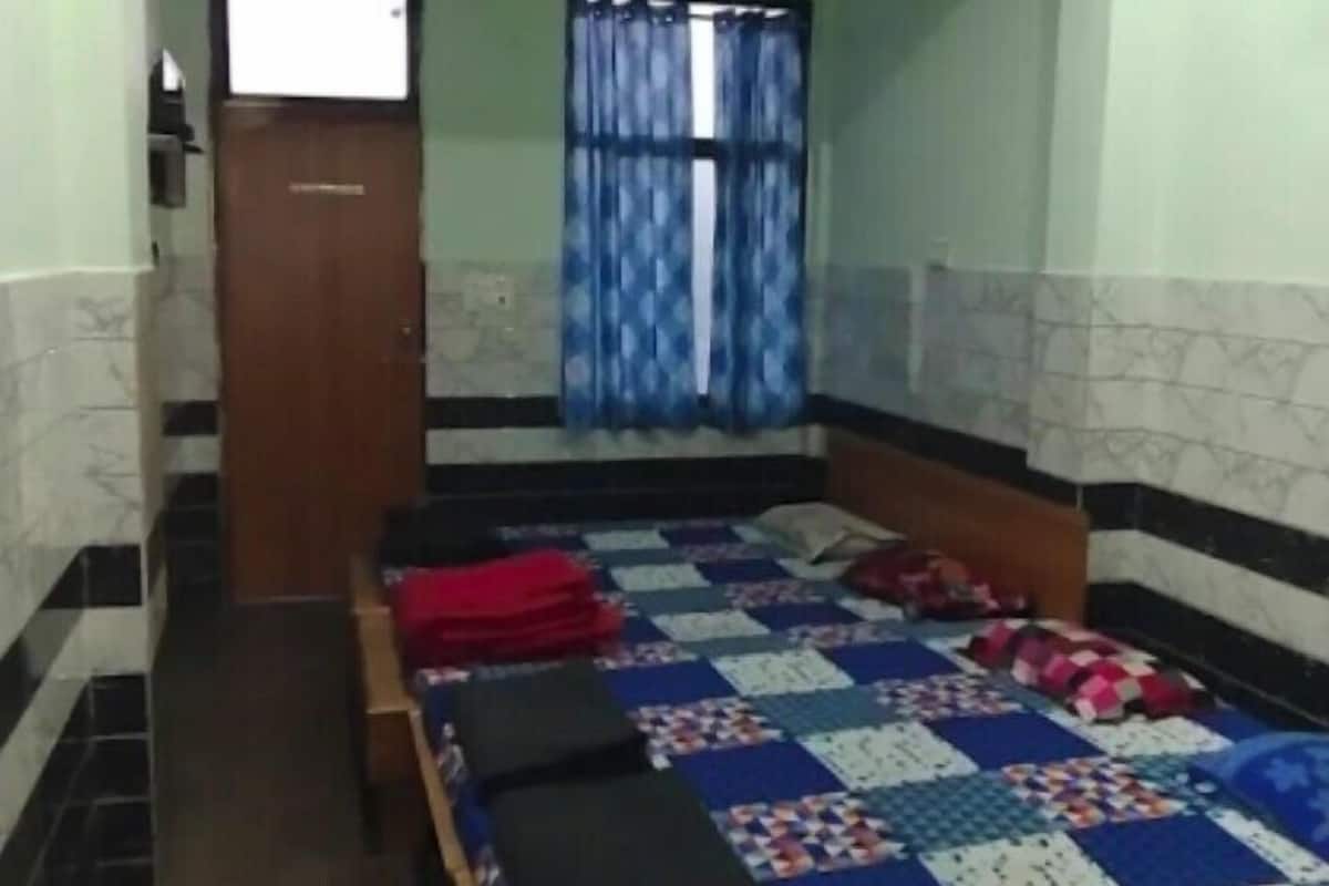 Un dormitorio con una cama, una puerta de madera, una ventana con cortinas y un ventilador de techo.