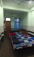 Un dormitorio con una cama, una puerta de madera, una ventana con cortinas y un ventilador de techo.