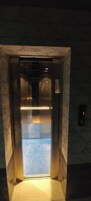 Un ascensor con pared de mármol y suelo iluminado.
