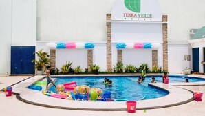 Área interna de piscina com várias piscinas, brinquedos infláveis e uma placa indicando o Hotel Terra Verde.