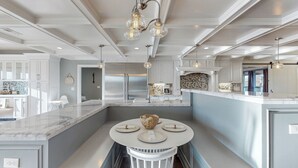 A modern kitchen with a marble island, stainless steel appliances, and pendant lighting.