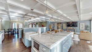 A spacious kitchen with marble countertops, a large island, and pendant lighting.
