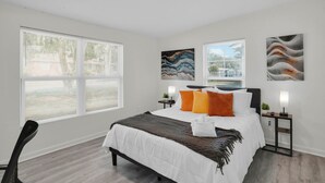 A modern bedroom with a large bed, two bedside tables, and artwork on the walls.