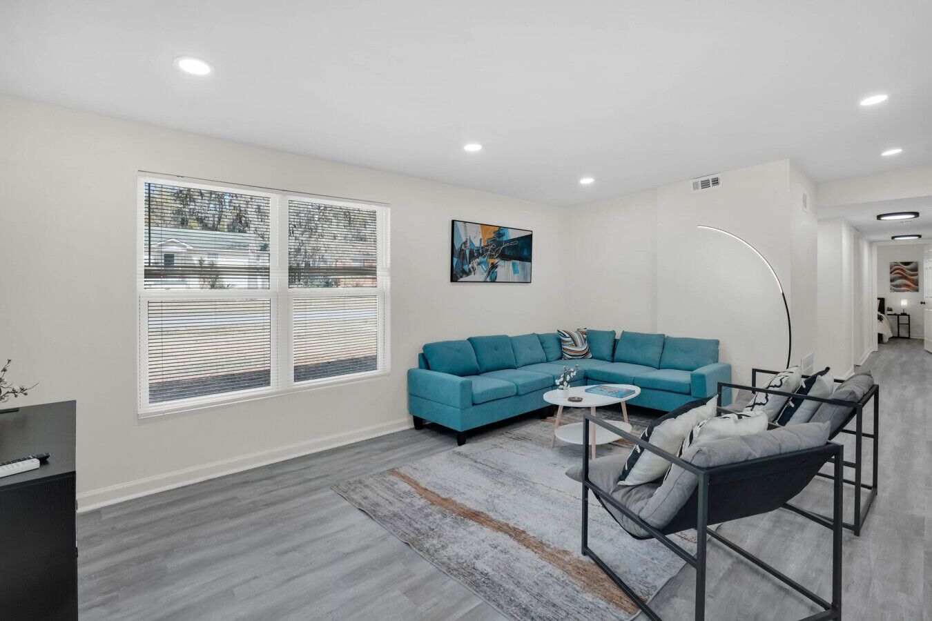 A modern living room with a teal sectional sofa, a round coffee table, and a floor lamp.