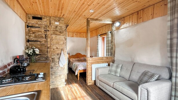 Une chambre confortable de style cabane, équipée d’une kitchenette, d’un lit et d’un canapé.