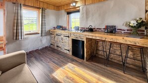 Une cuisine avec des meubles en bois, un lave-vaisselle encastré, un comptoir-bar avec des tabourets et une fenêtre donnant sur un espace verdoyant.