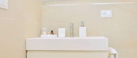 A bathroom with a white vanity, a mirror, and a towel rack.