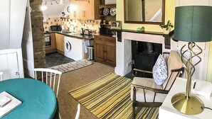 A compact kitchen with a washing machine, a sink, and a stove. There is a dining area with a table and chairs. - 2 bedroom accommodation in Weobley, Herefordshire (Weobley, Herefordshire)