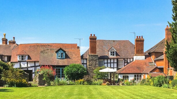 A traditional British house with a well-maintained lawn, stone walls, and multiple chimneys. - 2 bedroom accommodation in Weobley, Herefordshire (Weobley, Herefordshire)