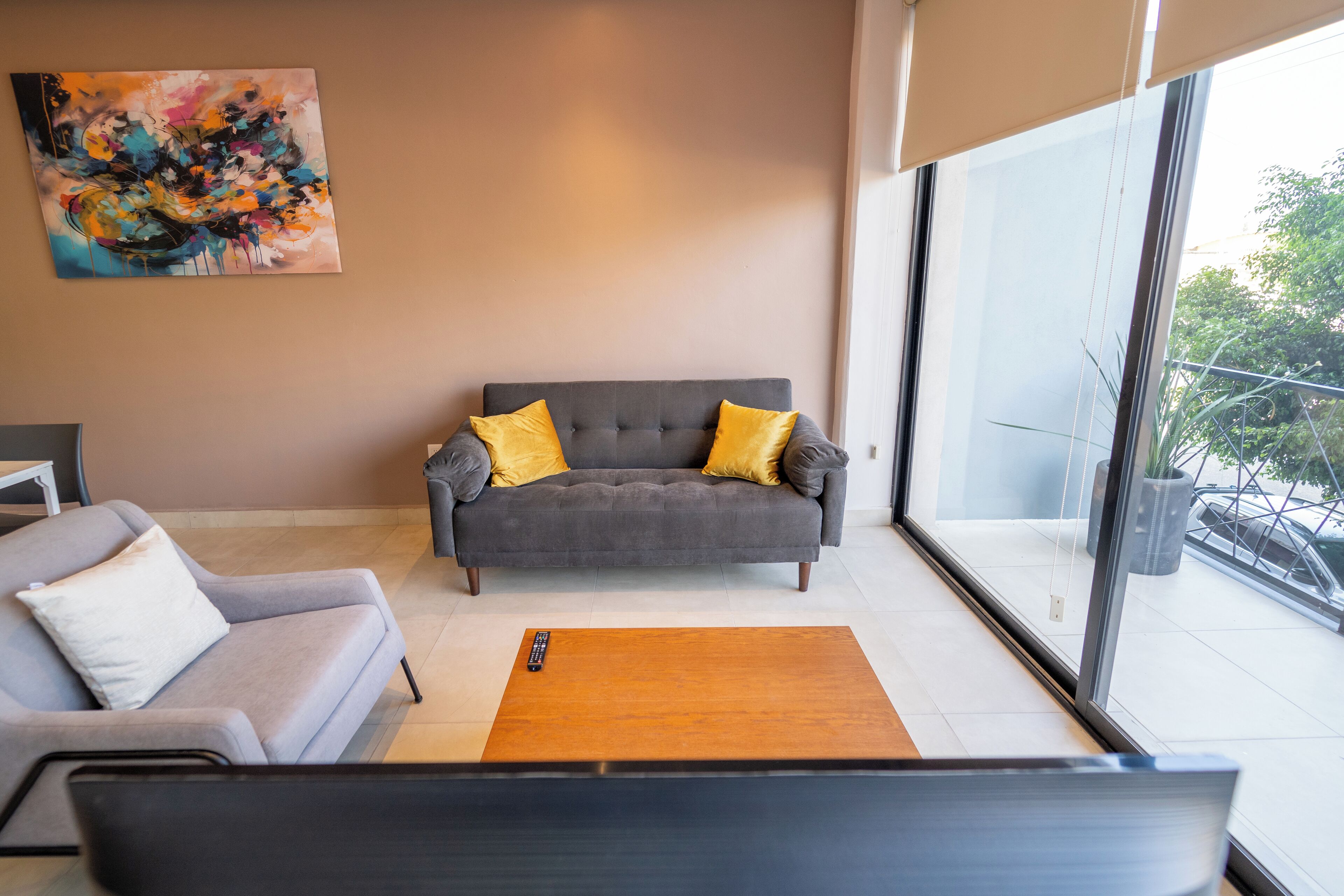 Ein modernes Wohnzimmer mit einem grauen Sofa, einem Holztisch und einer Fernbedienung darauf.