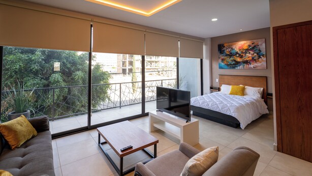 Ein modernes Schlafzimmer mit großem Fenster, einem Bett, einem Fernseher und einer Couch.