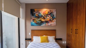 Ein Schlafzimmer mit einem großen Bett, einem Holzschrank, einem Bild an der Wand und einer Glastür.
