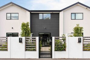 A modern two-story residential building with a dark central section and light-colored walls. - Exceptional Value For Money Sunny Warm 5 Mins CBD (Christchurch)