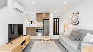 Una sala de estar moderna con una televisión de pantalla plana, un sofá gris y una mesa de centro.