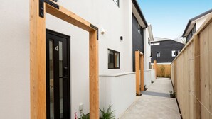 Un sendero estrecho y pavimentado entre dos casas modernas con detalles de madera y una puerta negra con el número 4.