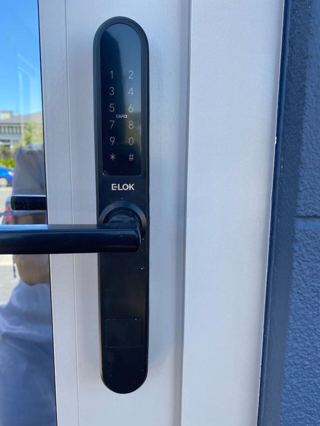 Uma porta moderna com teclado numérico e leitor de cartão, identificada como 'ELOK'.