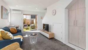 Una sala de estar moderna con sofá, televisor y un amplio armario.
