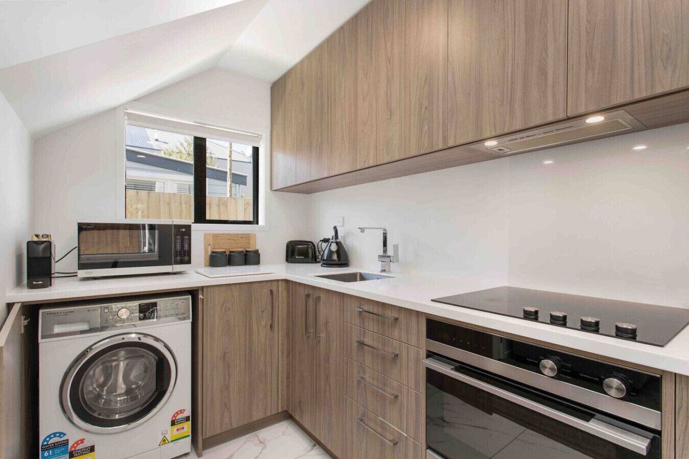 A compact kitchen with a washing machine, microwave, toaster, and oven.