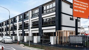 En modern byggnad med flera våningar, vit fasad och mörka detaljer.
