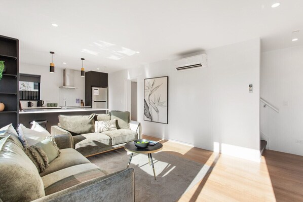 A modern living room with a sofa set, a coffee table, and a painting on the wall.