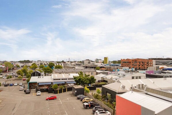 A parking lot with several cars, surrounded by buildings with flat roofs and commercial establishments.